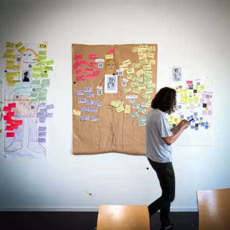 Eine Frau steht vor einer Wand mit Post-it-Zetteln